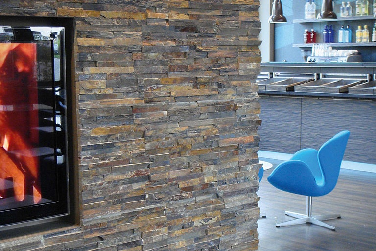 Decorarea pereților cu furnire din piatră naturală lângă șemineu și locuri albastre.