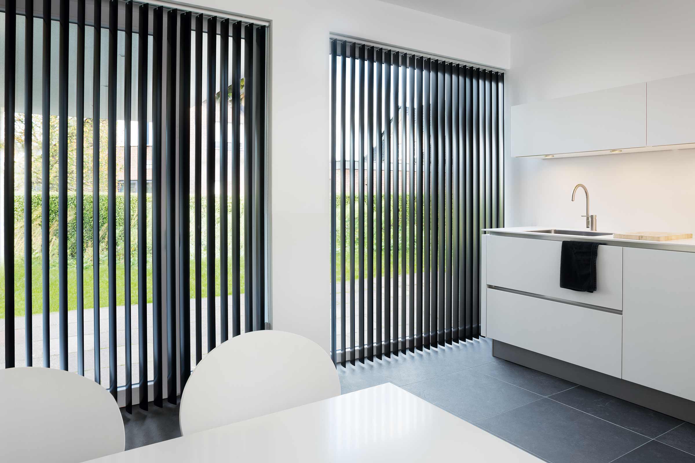 Interior modern cu jaluzele verticale pentru ferestre, masă de bucătărie și chiuvetă