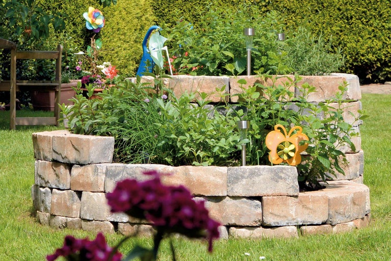 Jardinieră supraînălțată din pietre în grădină cu ierburi și decorațiuni de grădină