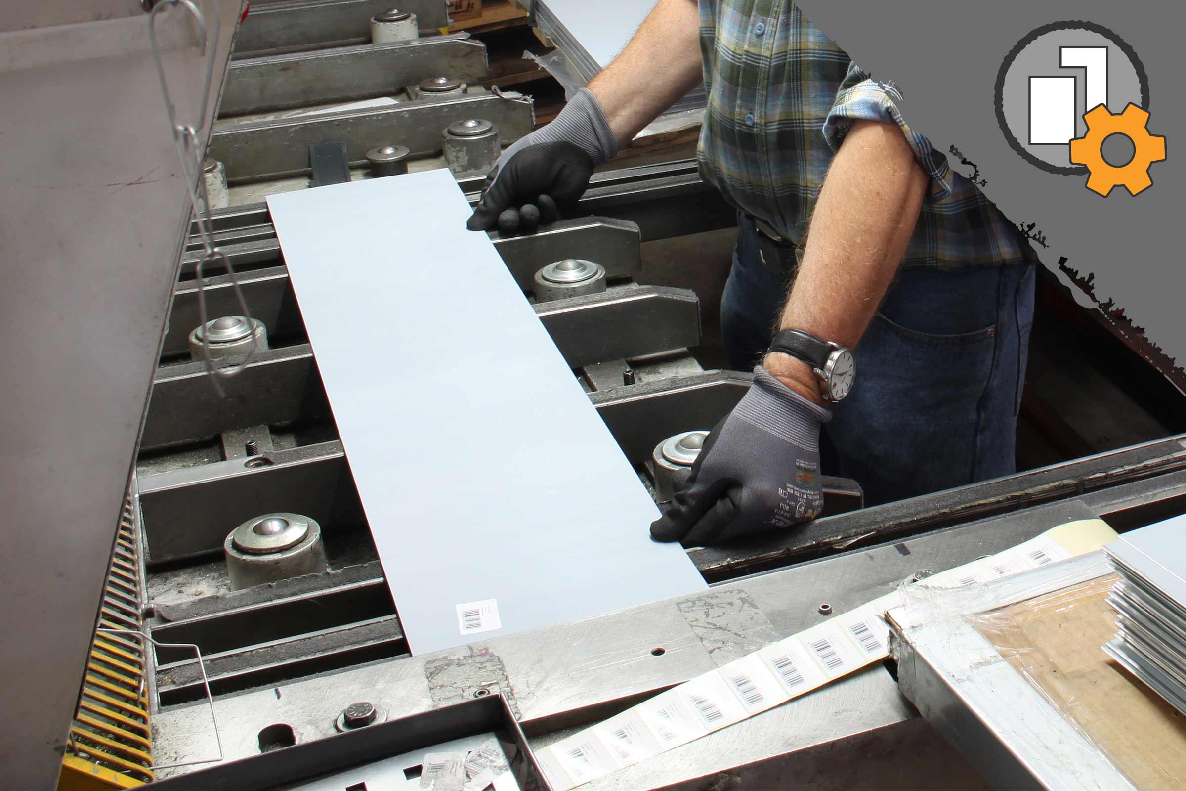 Un muncitor poziționează o placă metalică într-o mașină.