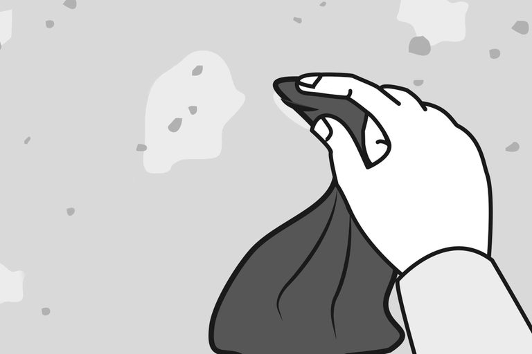 O mână șterge o suprafață neuniformă cu o cârpă.