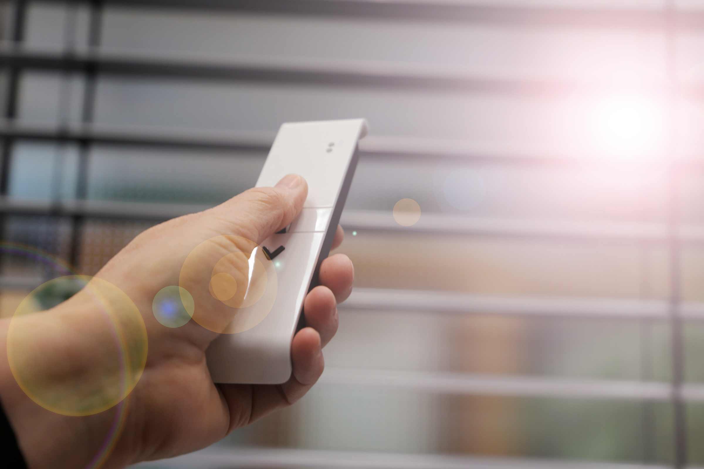 Mână ținând telecomanda pentru jaluzele