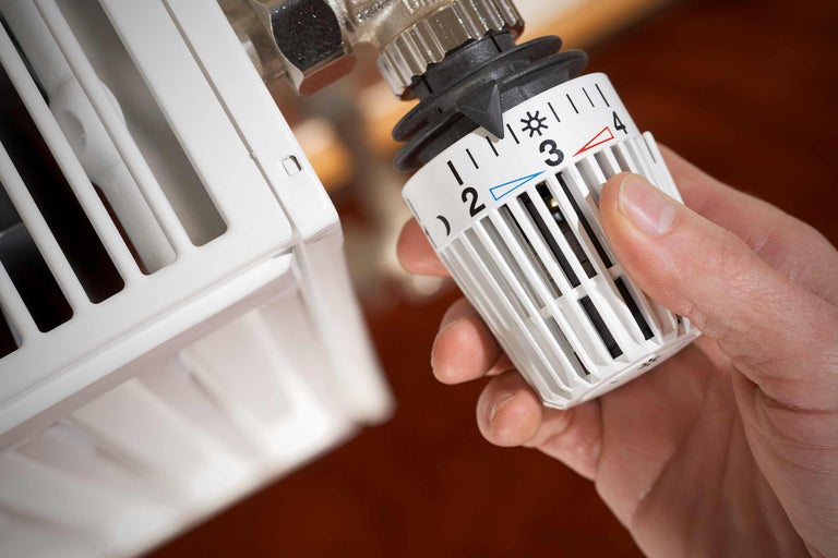 Prim-plan cu un termostat de calorifer reglat de o mână