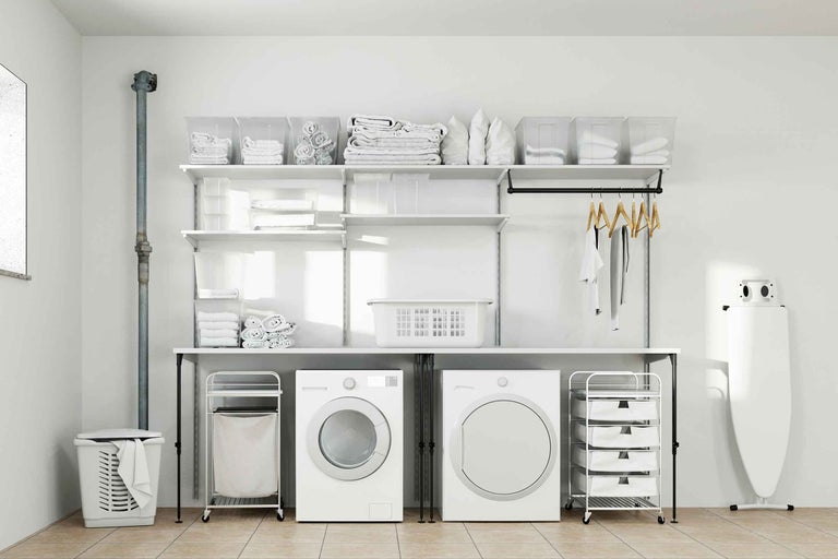 Spălătorie luminoasă cu mașină de spălat, uscător, rafturi și coșuri de rufe
