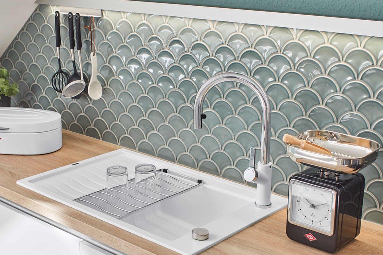 Scenă de bucătărie cu chiuvetă, robinet, suport pentru prosoape, ustensile de bucătărie și faianță