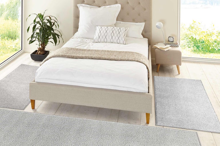 Dormitor luminos cu pat, noptieră și covor