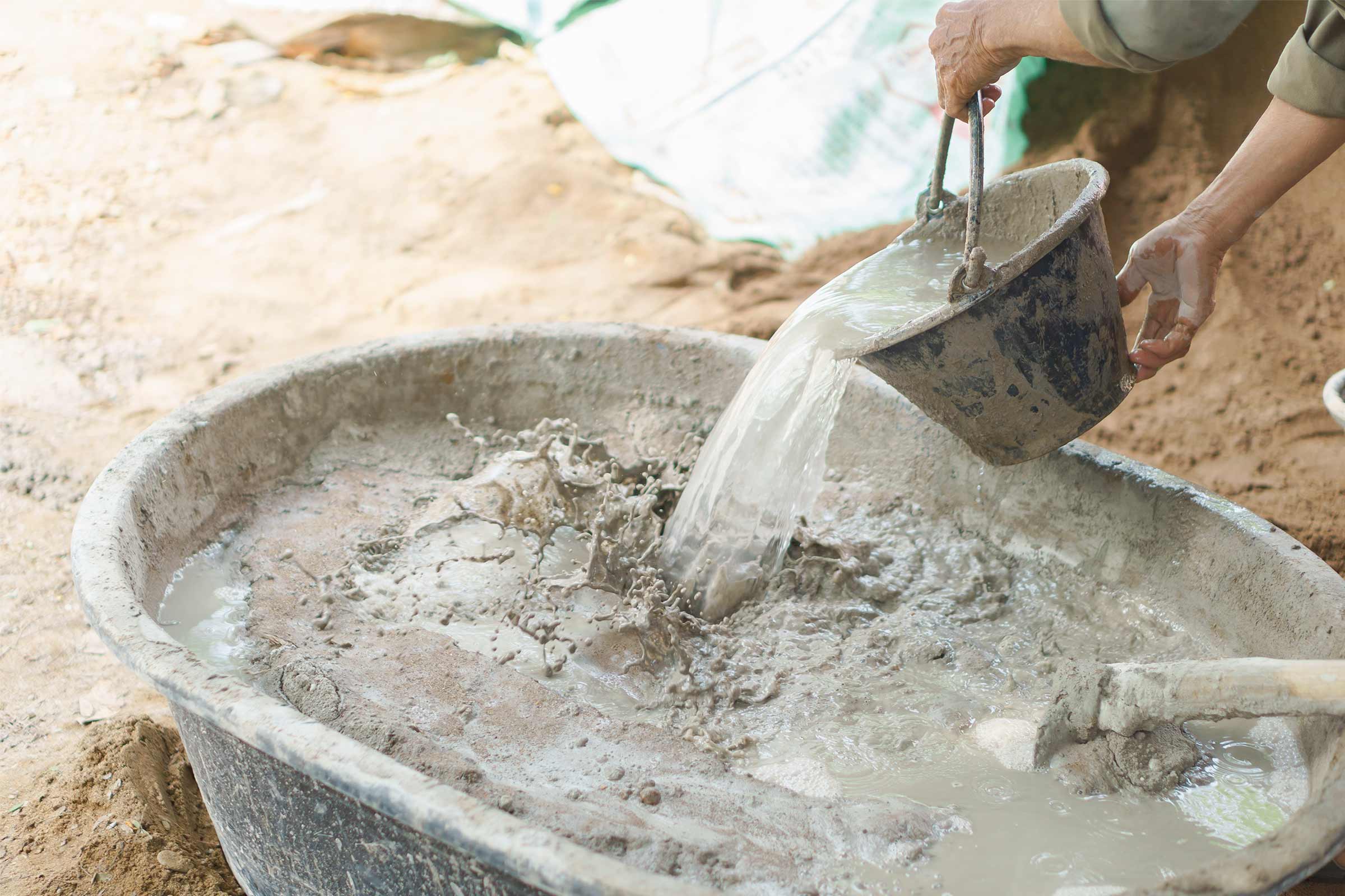 Amestecarea betonului într-o cuvă de mortar cu o găleată de apă.