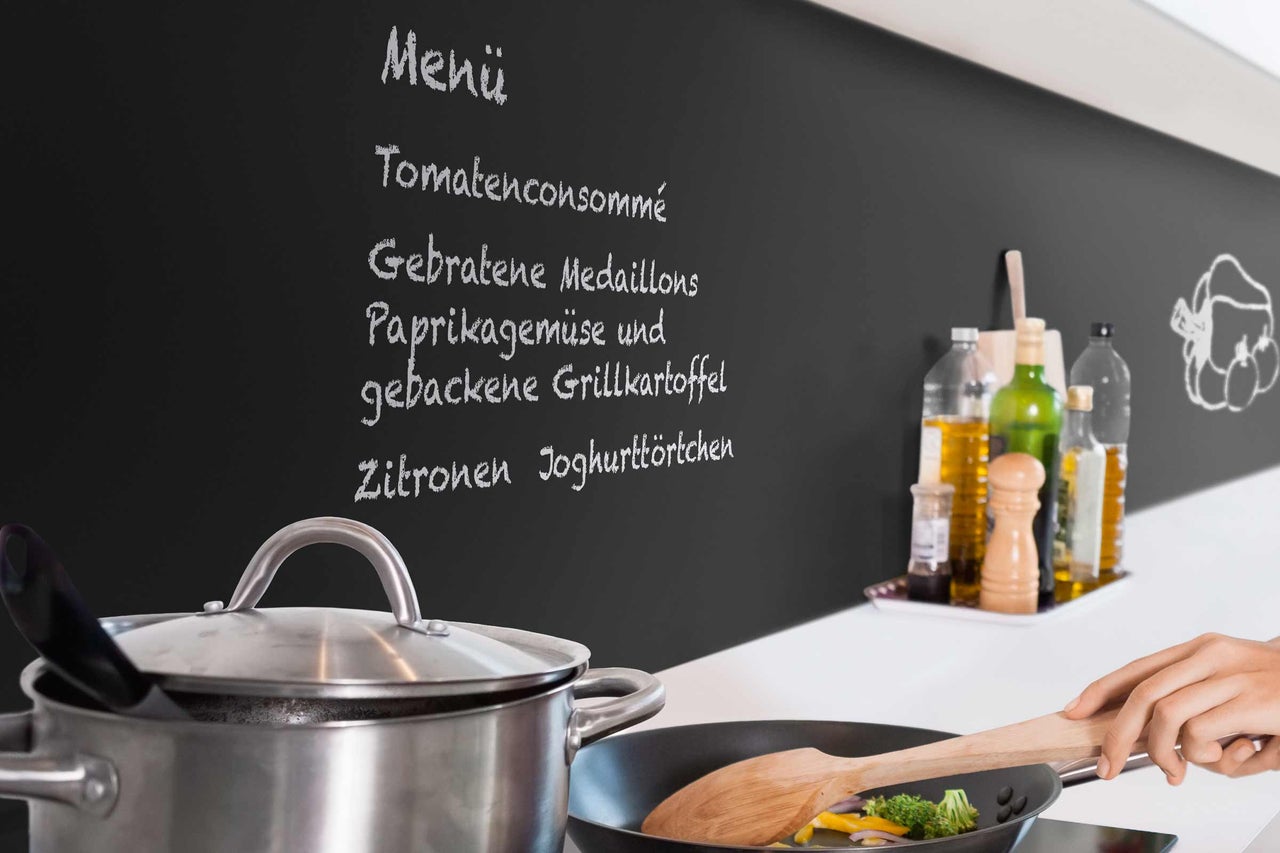 Scenă de bucătărie cu oală, tigaie și tablă de meniu scrisă de mână