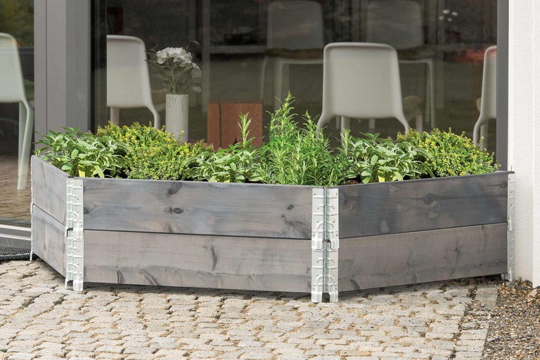 Jardinieră înaltă din lemn cu ierburi aromatice pe pavaj