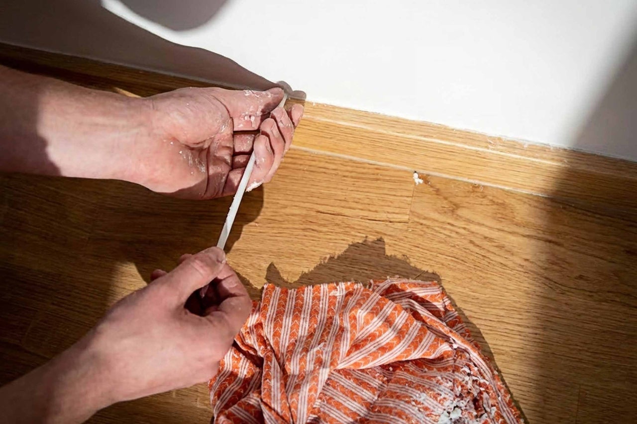 Curățarea unei plinte cu șpaclu și cârpă