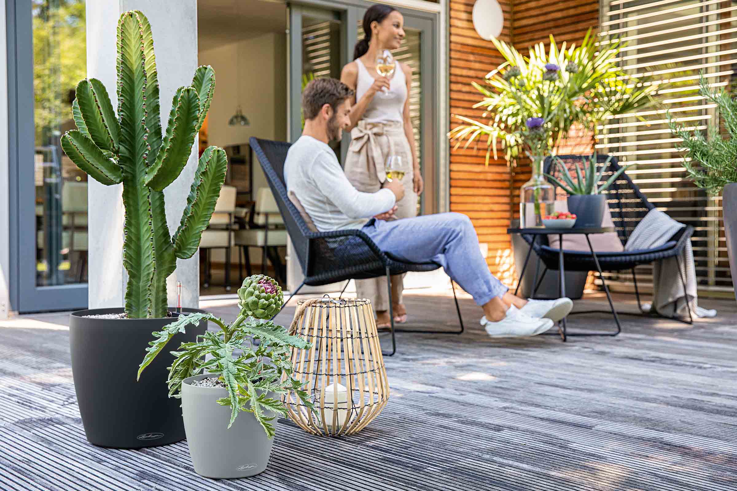Terasa cu zonă de relaxare, plante în ghivece și lanternă decorativă pentru o atmosferă relaxantă în aer liber
