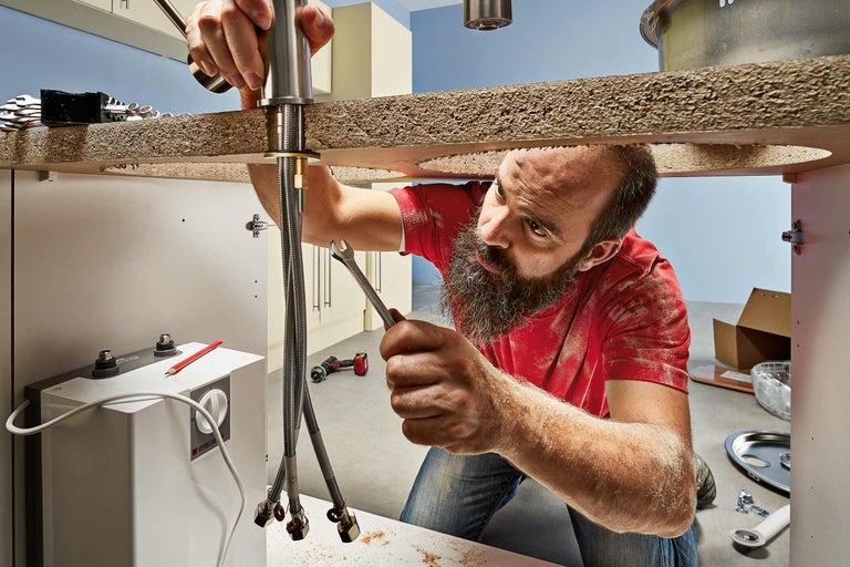 Un meseriaș instalează o baterie de chiuvetă într-o baie.