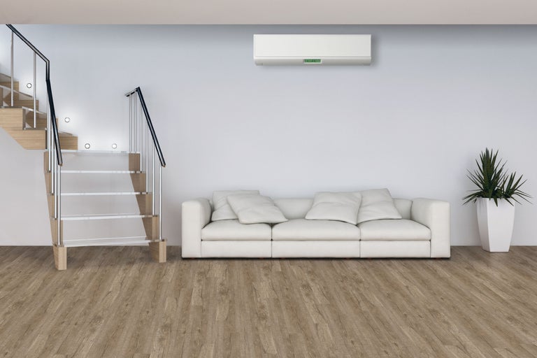 Cameră de zi luminoasă cu scară, aer condiționat, canapea și plantă de interior
