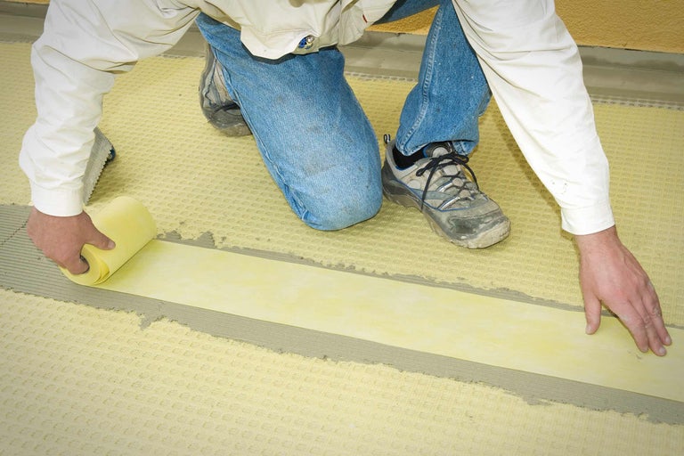 Artizan așază bandă de etanșare pe o folie de separare