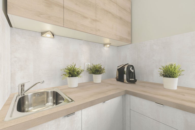 Bucătărie luminoasă cu chiuvetă, blat de lucru, dulapuri suspendate și iluminare sub dulap