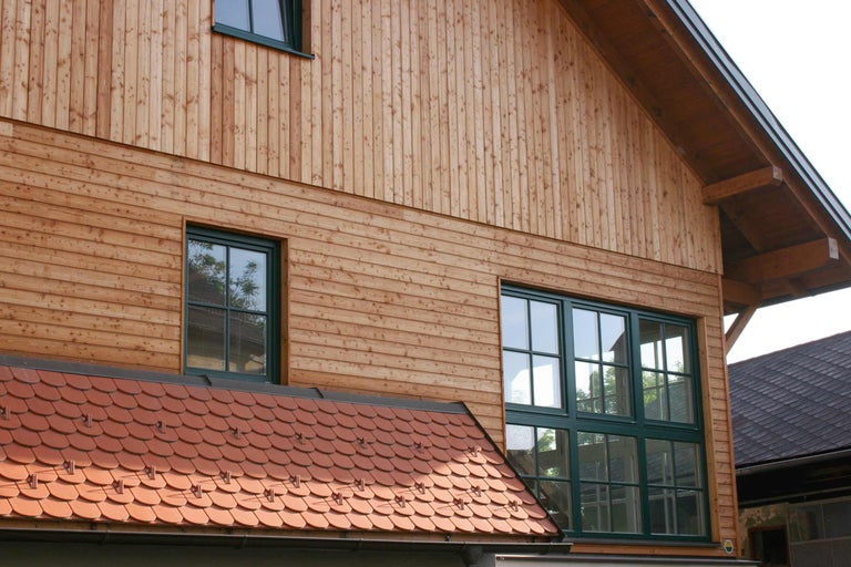 Fațada unei case cu placare din lemn și ferestre