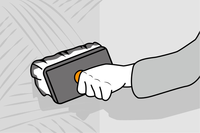 Mână aplicând o drișcă pe un perete