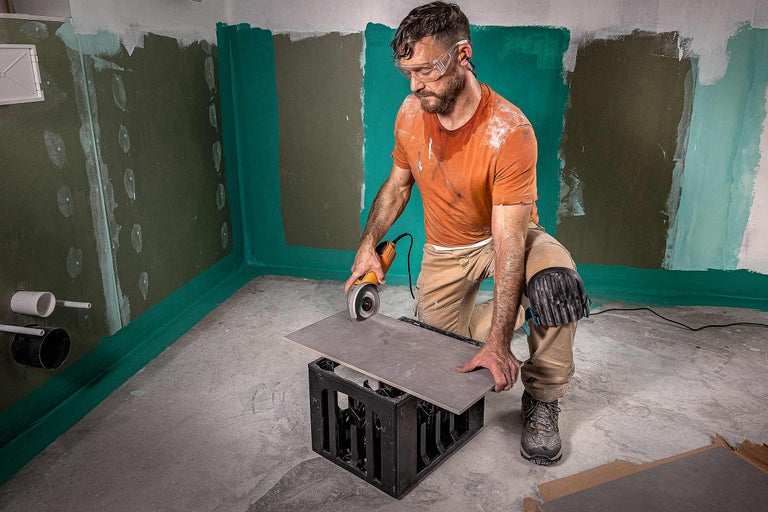 Artizan care taie o faianță cu un polizor unghiular în baie