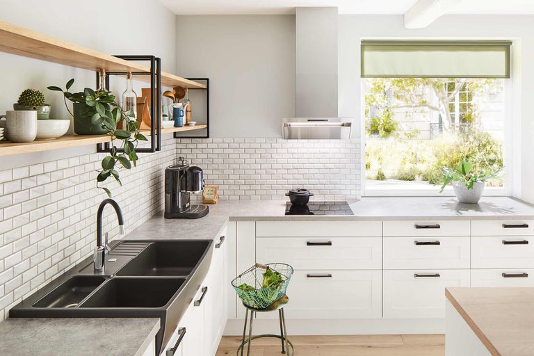 Bucătărie luminoasă cu chiuvetă, plită, hotă, faianță și rafturi