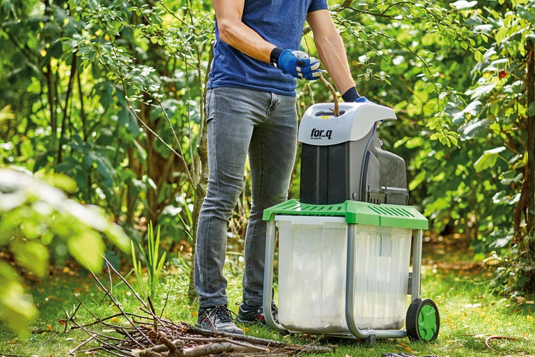 Un bărbat operează un tocător în grădină pentru a toca ramuri