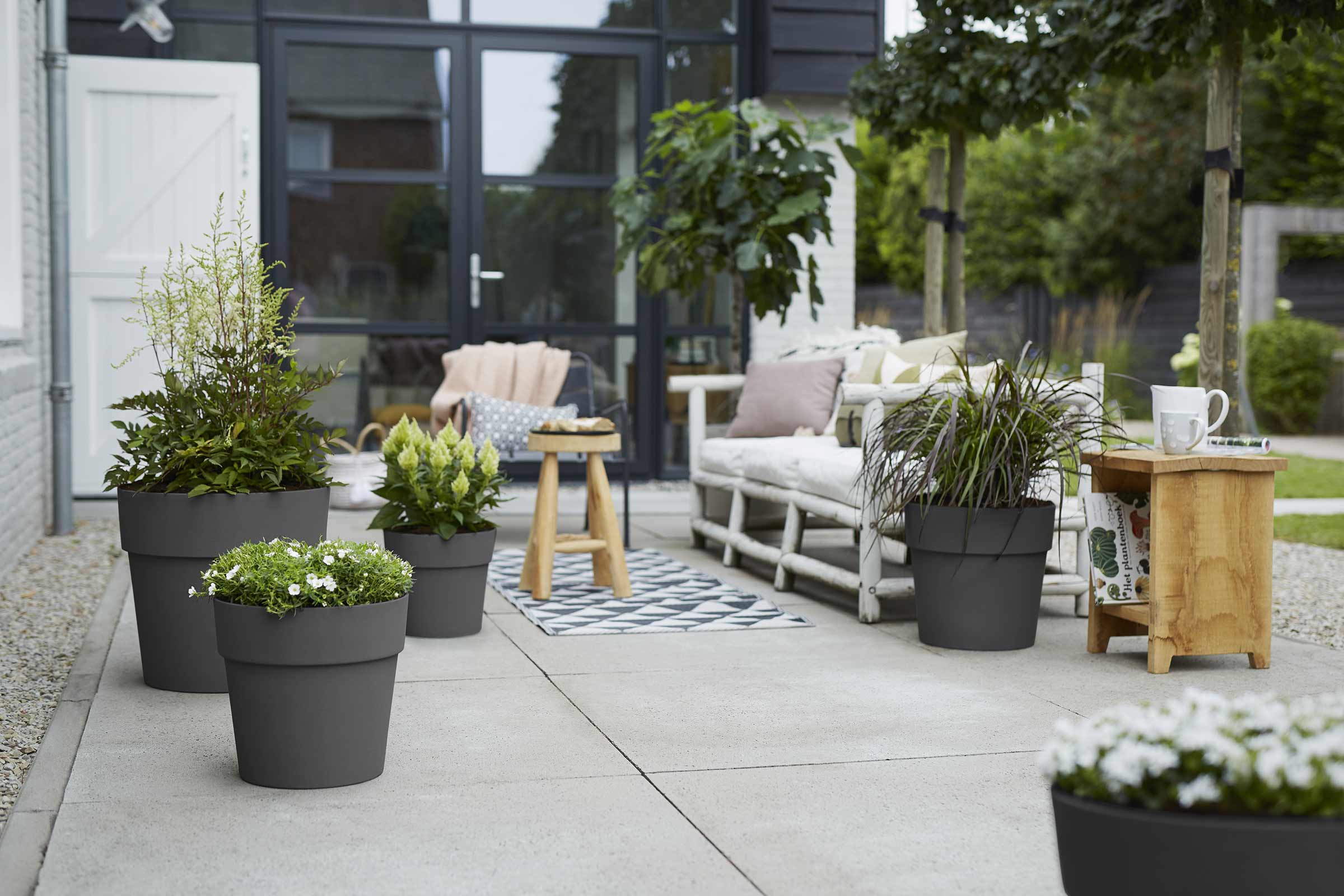 Scenă decorativă de grădină cu jardiniere plantate, zonă de relaxare și elemente din lemn