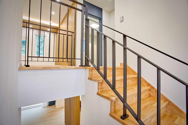 Scară din lemn cu balustradă metalică într-o casă luminoasă.