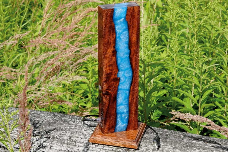 Lampă de masă decorativă din lemn și rășină sintetică în fața plantelor