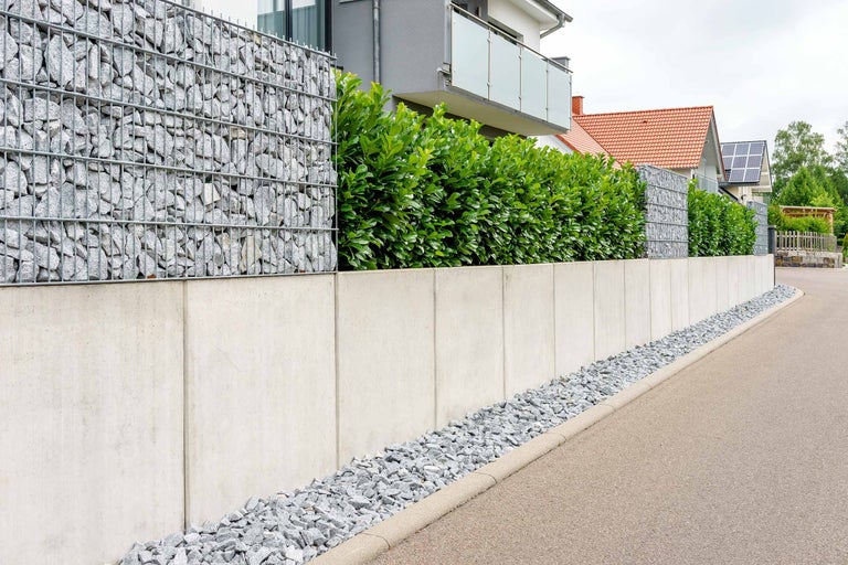 Zid de gabioane combinat cu elemente de beton și plante verzi ca protecție vizuală în grădină