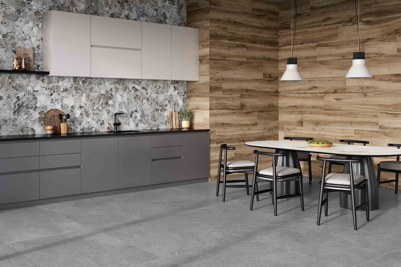 Bucătărie luminoasă, spațioasă, cu podea cu gresie gri, blat, perete posterior și perete din lemn