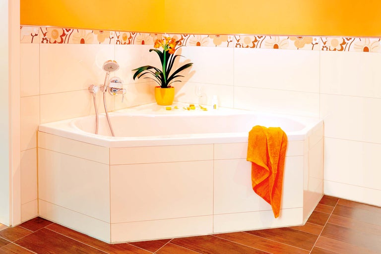 Cadă de colț într-o baie cu gresie și decorațiuni