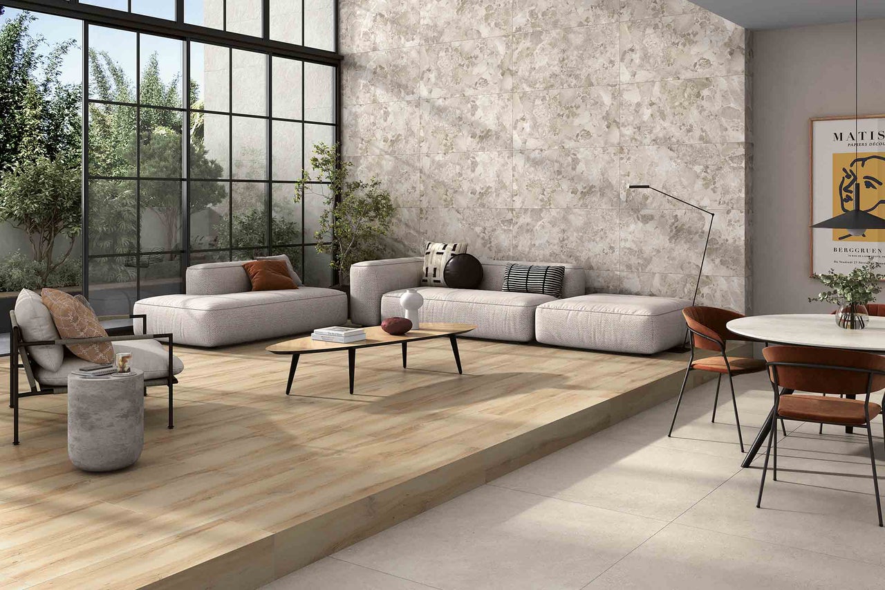 Cameră de zi luminoasă, cu podea cu gresie aspect lemn, zonă de relaxare și fațadă cu ferestre mari.