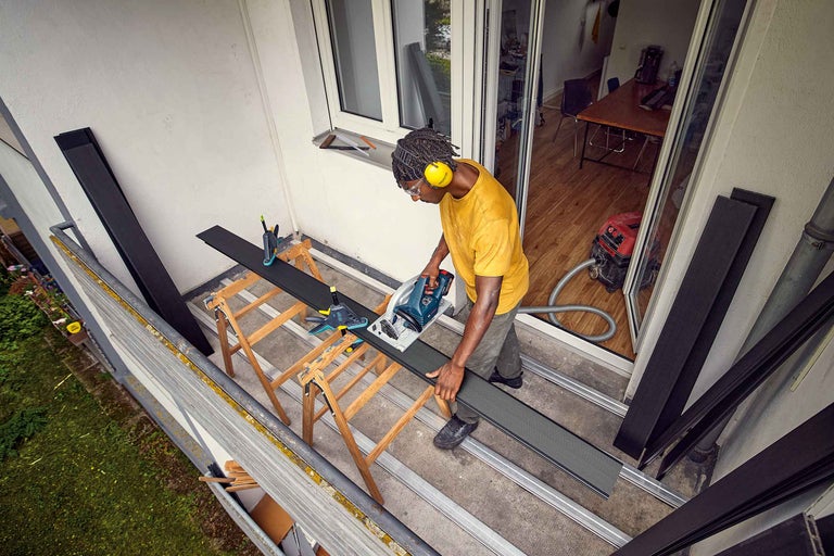 Bărbat care instalează o terasă din lemn cu o menghină