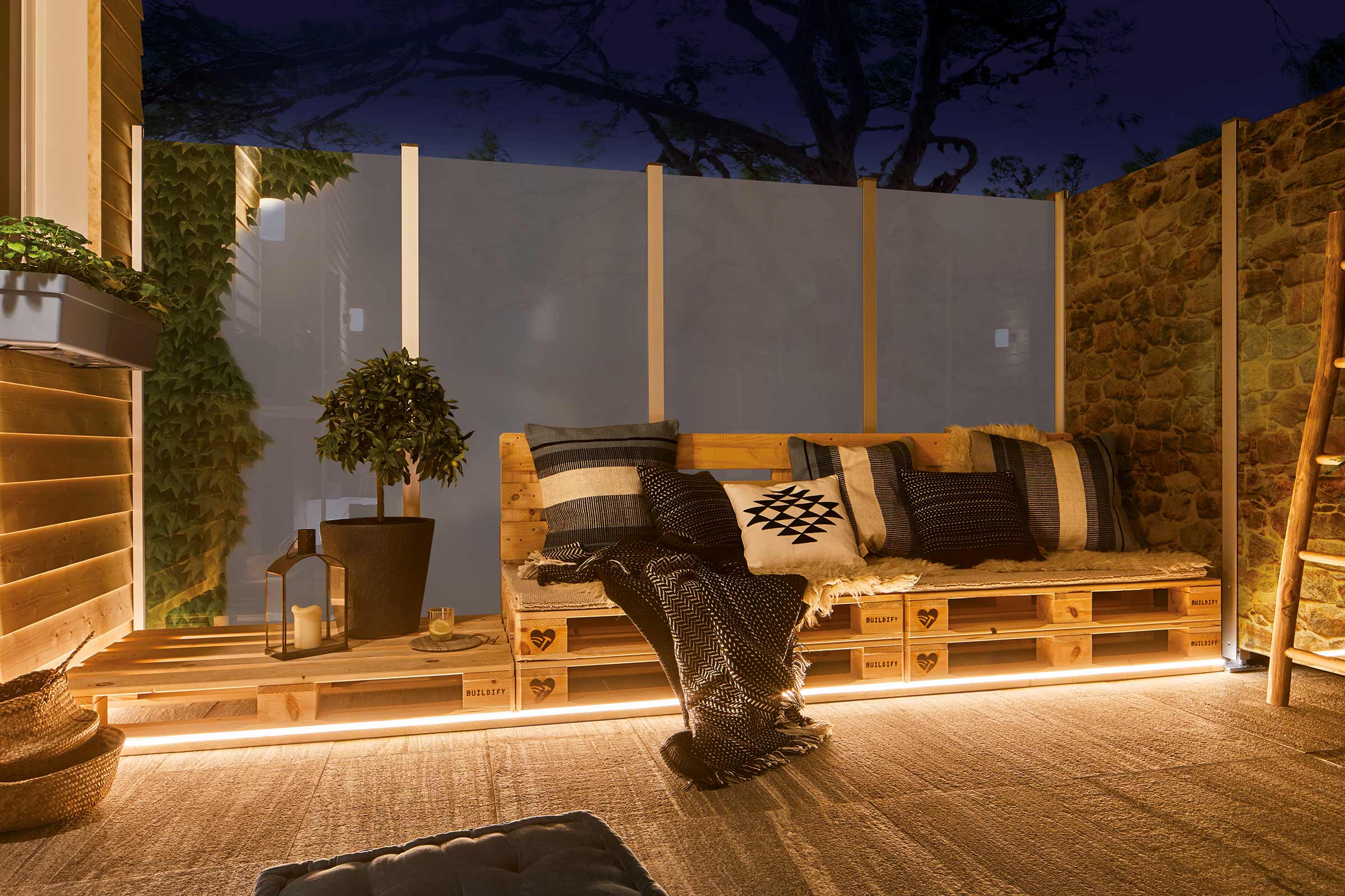 Terasa amenajată cu mobilier din lemn, plante și iluminat decorativ pentru o atmosferă exterioară primitoare.