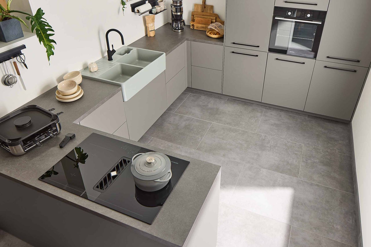 Bucătărie luminoasă cu chiuvetă, plită, hotă, cuptor și ustensile de bucătărie.