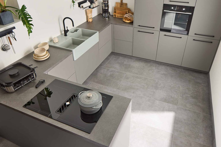 Bucătărie luminoasă cu chiuvetă, plită, hotă, cuptor și ustensile de bucătărie.