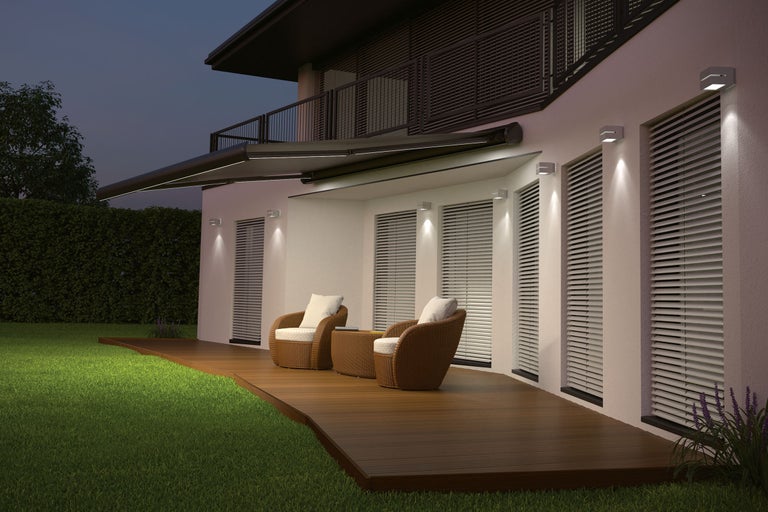 Fațadă de casă cu marchiză, iluminat exterior și grup de relaxare pe terasă din lemn