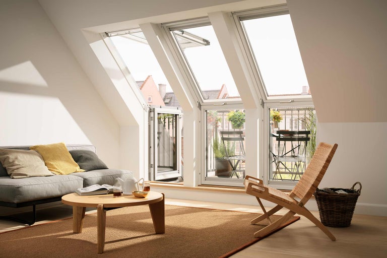 Cameră de zi luminoasă cu ferestre de mansardă, canapea și balcon