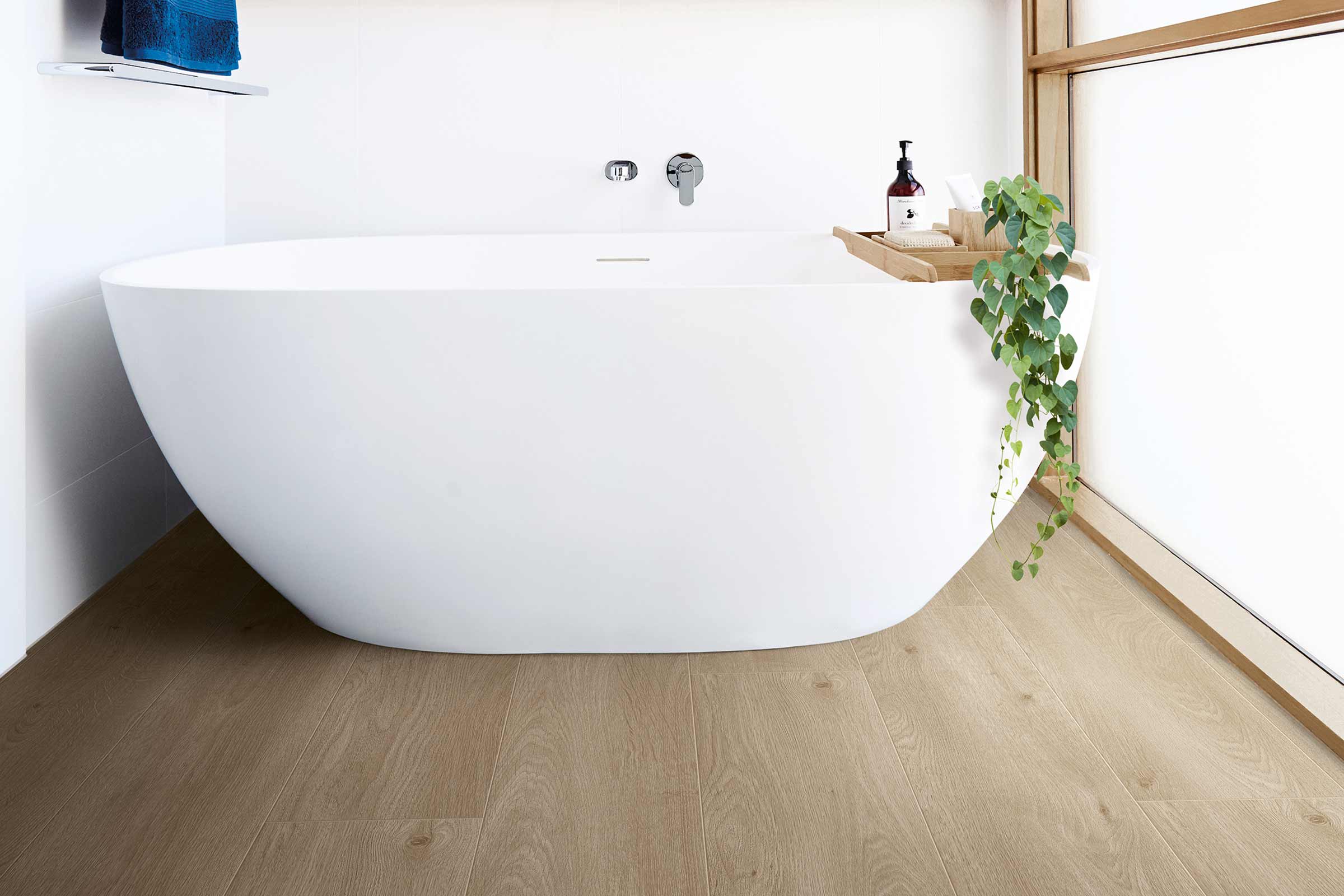 Baie modernă cu cadă independentă, podea din lemn și design minimalist.