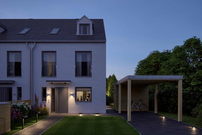 Exteriorul unei case moderne înșiruite cu carport la amurg