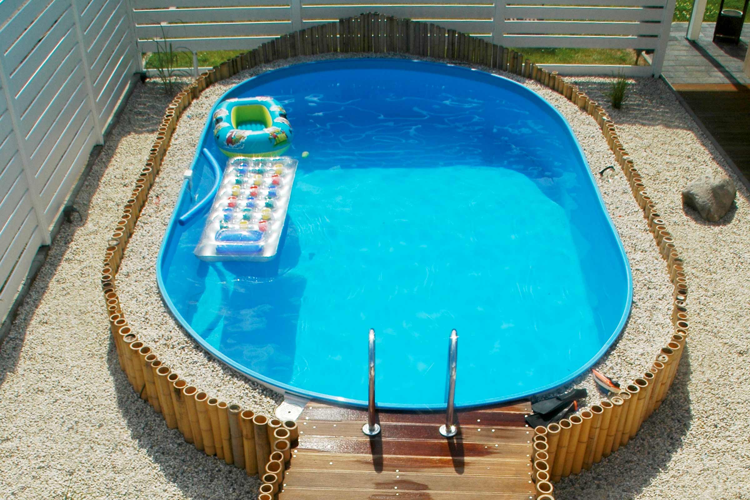 Piscină gonflabilă cu scară și margine de bambus în grădină.
