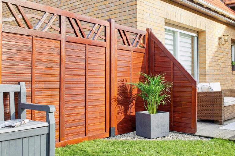 Gard de confidențialitate din lemn cu element decorativ și bancă de grădină în grădină