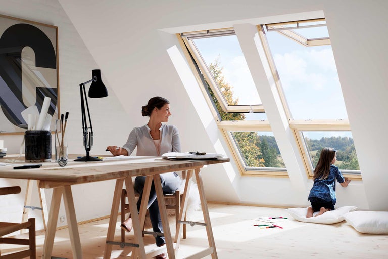 Mansardă luminoasă cu ferestre de mansardă, femeie la birou și copil la fereastră