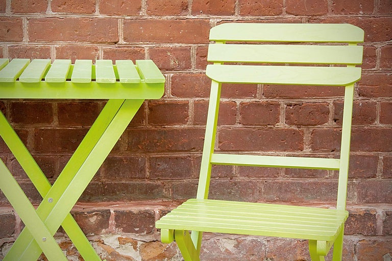 Măsuță de grădină și scaun de grădină din lemn în fața unui zid de cărămidă