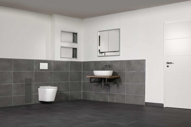 Baie cu WC suspendat, lavoar pe consolă de lemn, dulap cu oglindă și gresie gri.