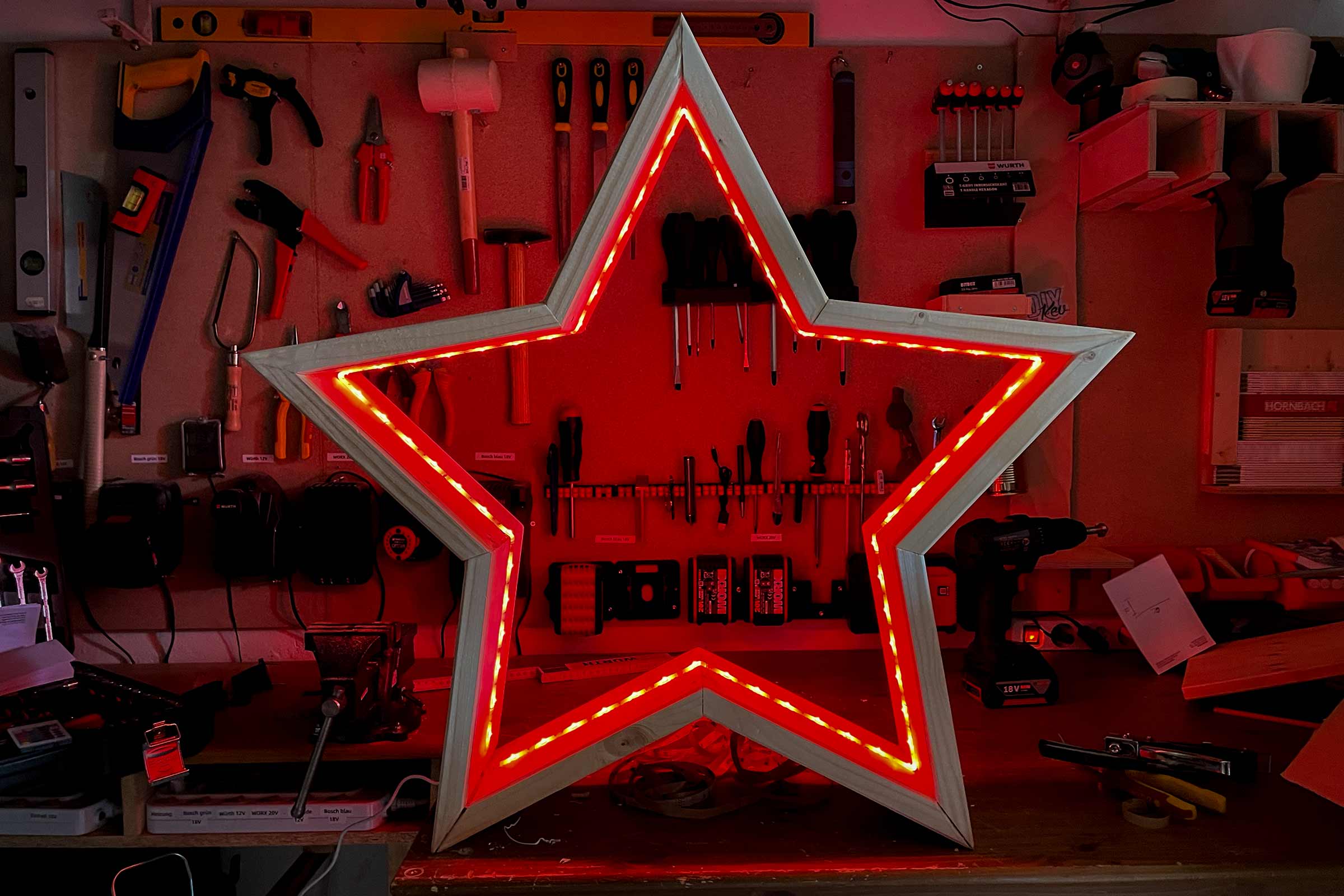 Stea din lemn cu iluminare cu LED-uri în fața unui perete cu scule