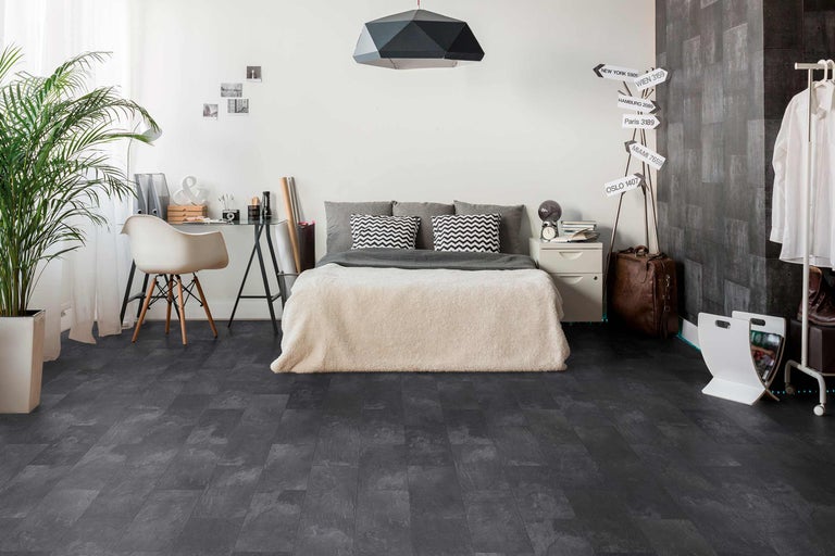 Dormitor cu pat, birou și podea întunecată cu aspect de piatră.