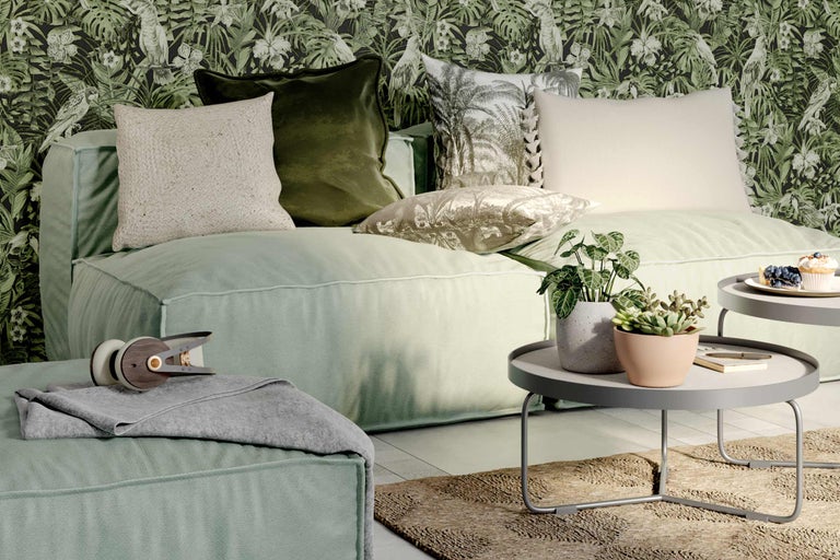 Cameră de zi cu canapea, perne, măsuță laterală și plante de interior în fața unui tapet cu model