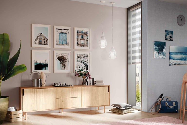 Cameră de zi cu comodă din lemn, tablouri, lămpi suspendate și decorațiuni pentru o ambianță confortabilă.