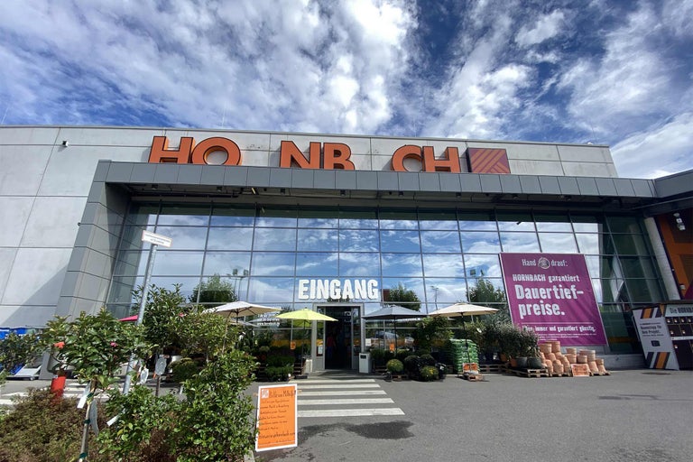 Fațada magazinului de bricolaj Hornbach cu zona de intrare și plante