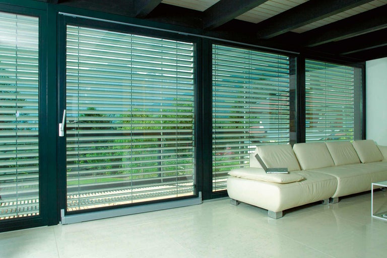 Imagine de interior a unui living cu ferestre mari și jaluzele